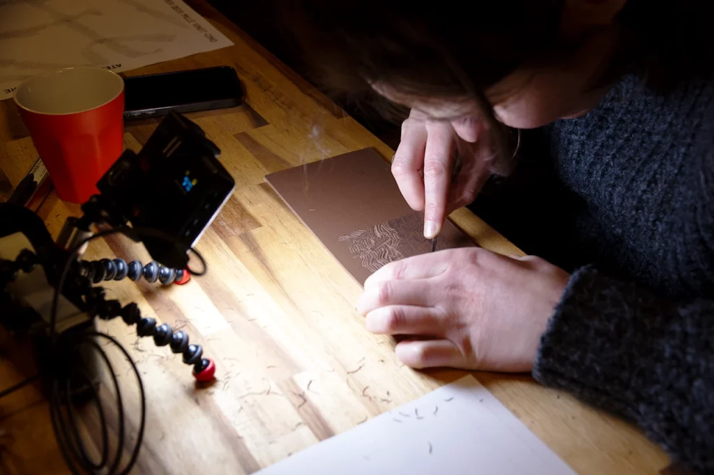 Mathilde gravant méticuleusement sa création graphique.