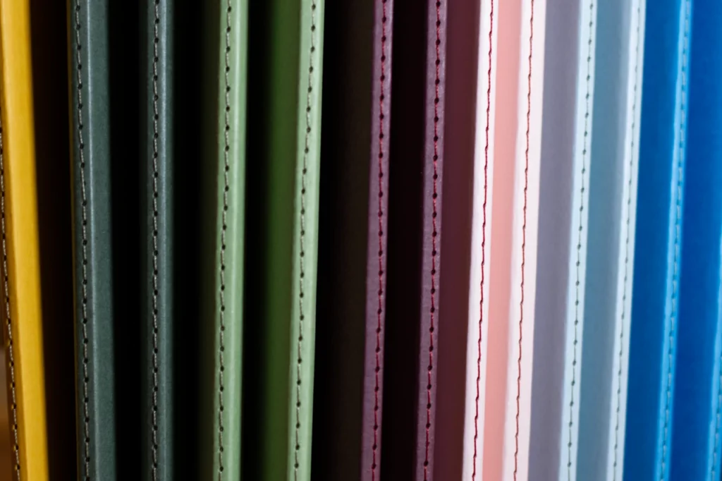 Carnets faits main à l'atelier Forme contre forme avec une reliure Singer et des couvertures colorées en vues de dos.