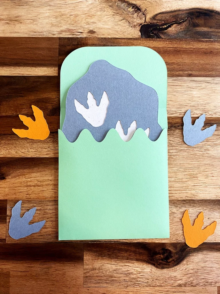 Enveloppe verte d'eau personnalisée, vue de dos, pour accueillir la carte d'invitation d'anniversaire sur le thème « dinosaure ».