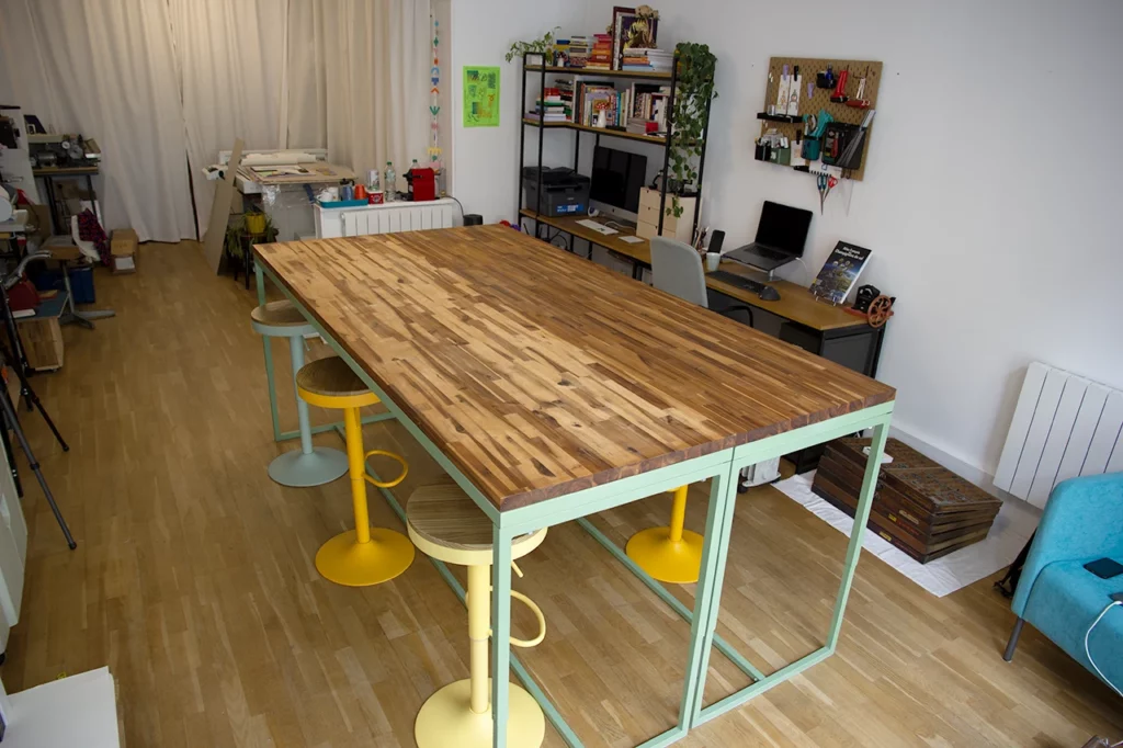 Table sur-mesure en bois et métal, vert olive, avec deux plateaux modulables en acacia, en position haute pour travailler debout.