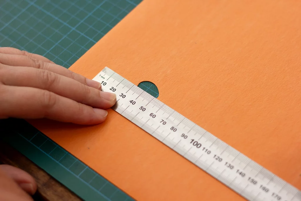 Étape de mesure avant contrecollage du carton gris sur le cuir de pomme.