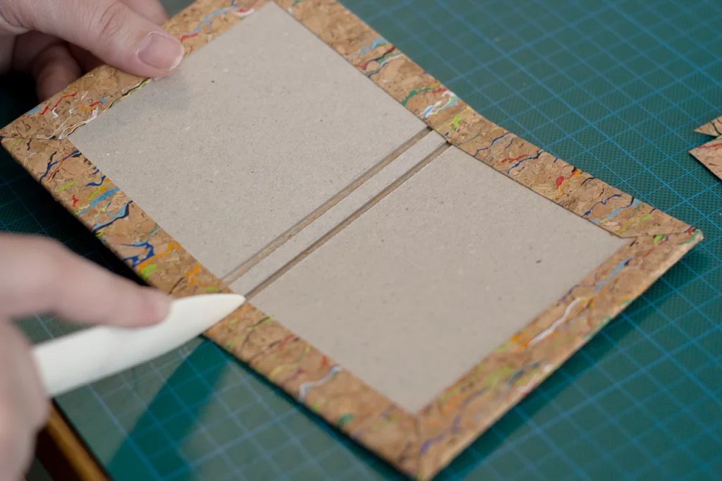 Finition du rembordage à l’aide d’un plioir, sur une couverture en toile de liège.