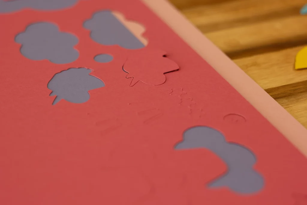 Formes de licornes et de nuages découpées dans du papier épais rose à l’aide de ma table de découpe, pour fabriquer le jeu de société "Au royaume des licornes".