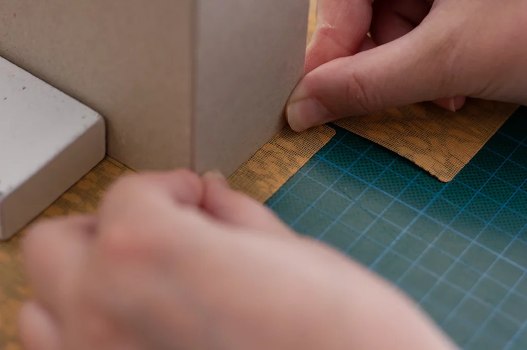 Zoom sur la mise en place du carton gris pour un porte-revues fait main en toile de liège.