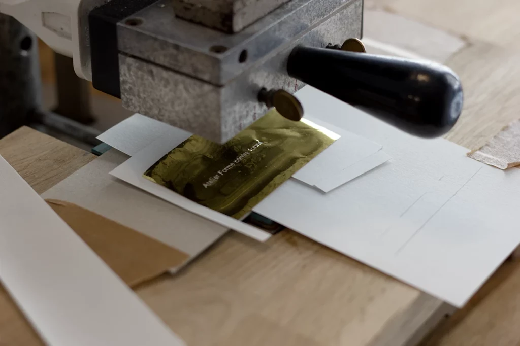 Dorure à chaud artisanale dorée, réalisée sur un papier de création pour être placée dans la cuvette de la couverture.