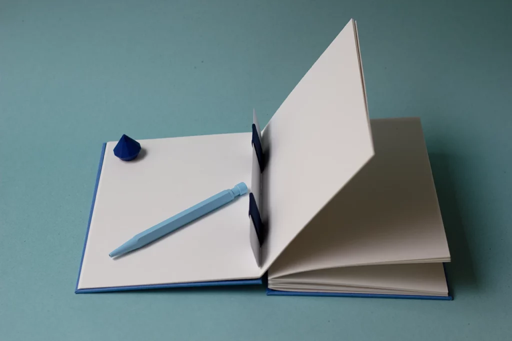 Carnet ouvert avec une reliure australienne à charnière piano inversée, style plat, montrant la charnière intérieure et le gond plat qui maintient les cahiers.