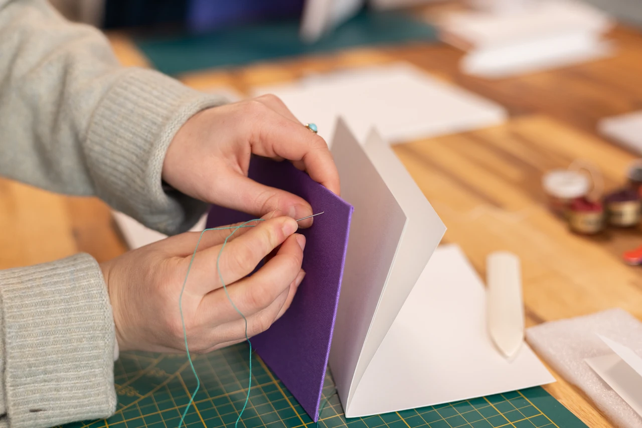 Assemblage de la couverture et des cahiers intérieurs d’un carnet lors d’un atelier de reliure dans mon atelier.