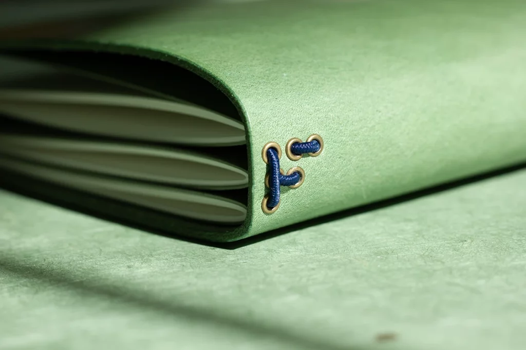Zoom sur le passage des élastiques dans des œillets en bronze formant un “F”, signature Forme contre forme.