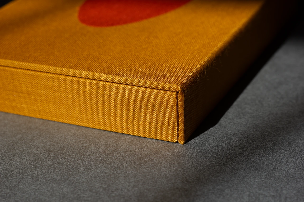 Zoom sur une boîte à rabat aimanté fermée, ornée d’une marqueterie de toile en forme de cœur orange — Atelier Forme contre forme, Bordeaux.